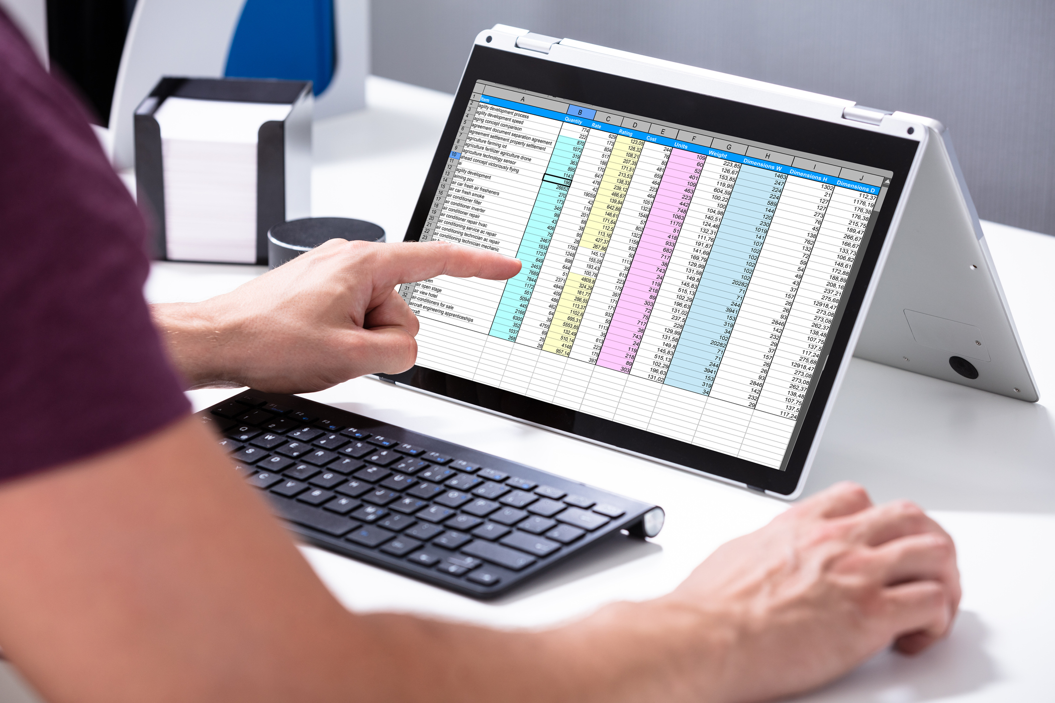 Businessman's Hand Examining Spreadsheet On Laptop In Office results driven